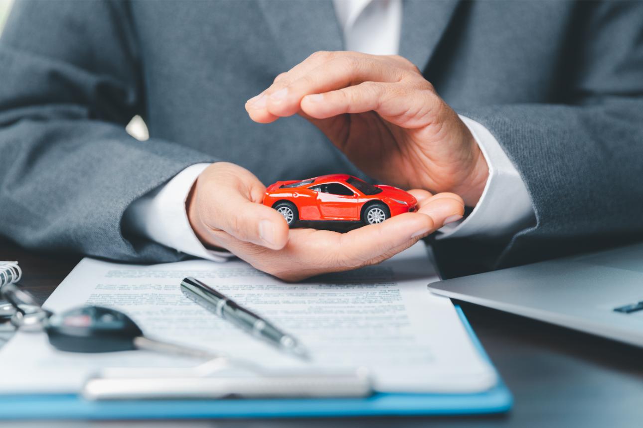 Persona sostiene un coche rojo en miniatura entre sus manos